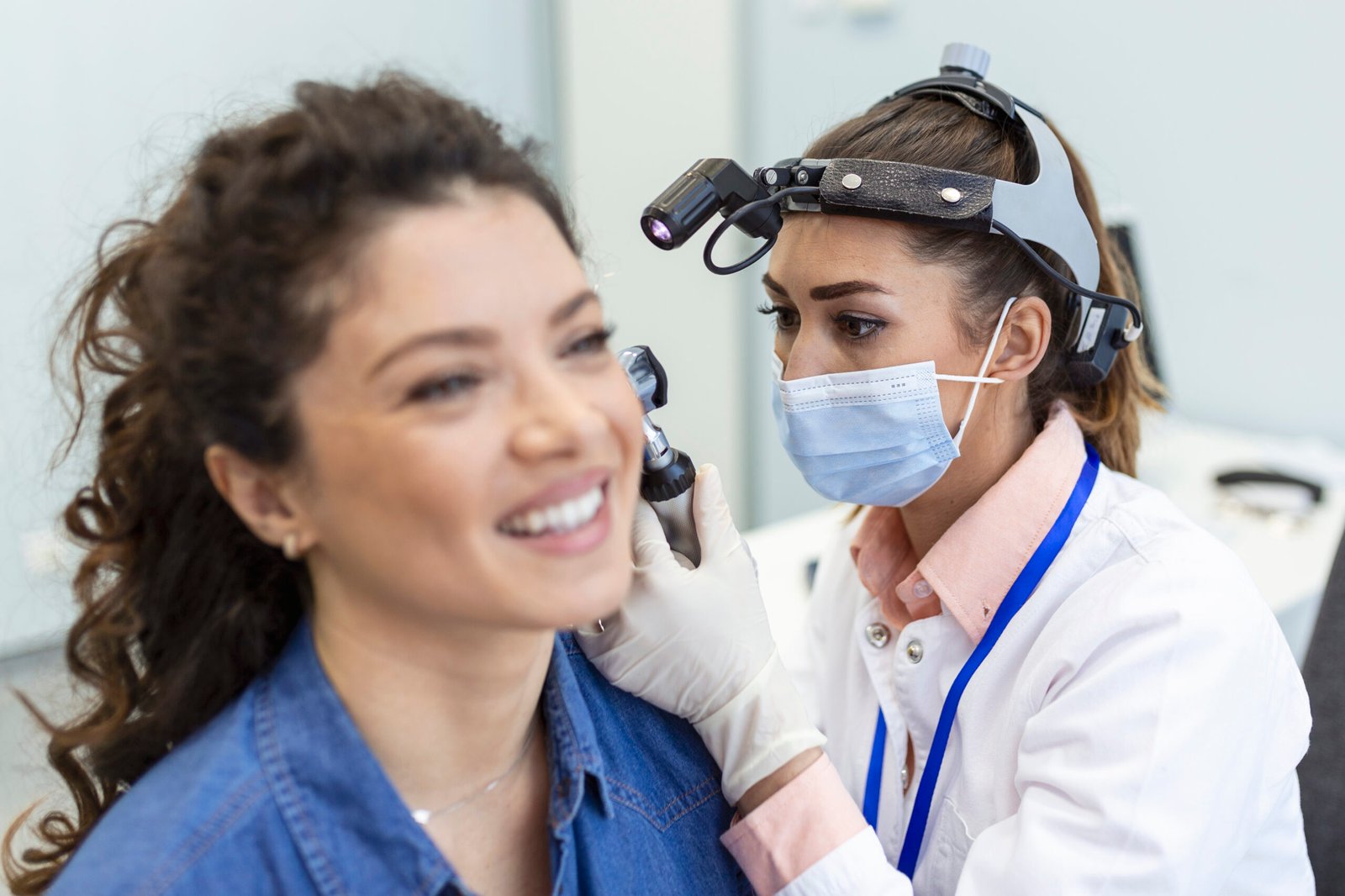 Hearing exam. Otolaryngologist doctor checking woman's ear using otoscope or auriscope at medical clinic.